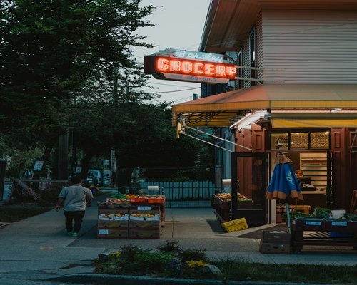 A person selecting fresh fruits at a small neighborhood store on a sunny day
